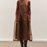 Person wearing a brown turtleneck and sheer brown skirt against a white background