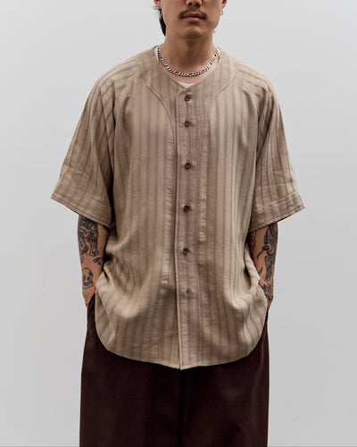 Man wearing a beige button-up shirt and dark pants against a plain background