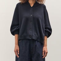 Person wearing a dark blue sweater and jeans on a plain background