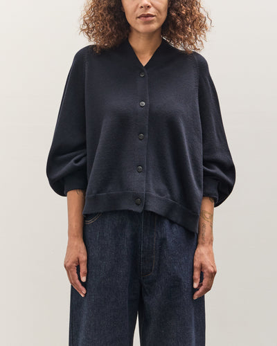 Person wearing a dark blue sweater and jeans on a plain background