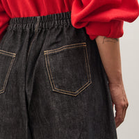 Person wearing a red sweater and dark jeans on a plain background