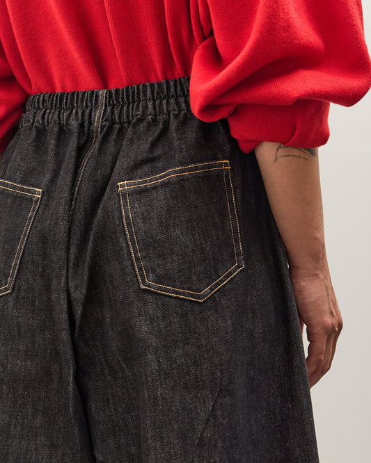 Person wearing a red sweater and dark jeans on a plain background