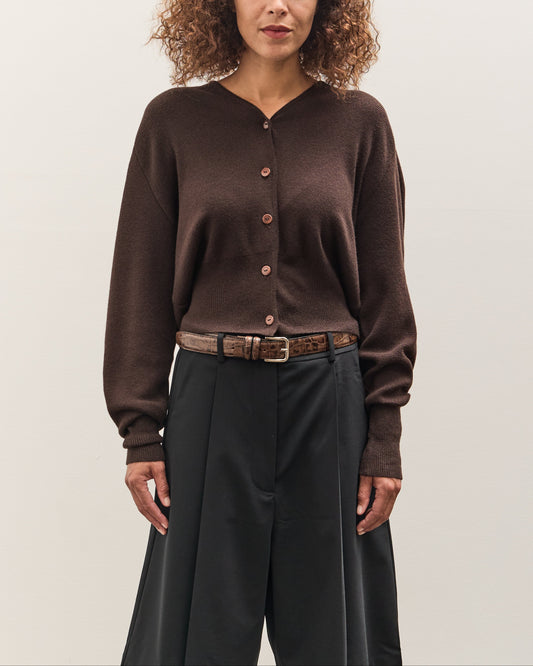 Woman wearing a brown cardigan and dark pants against a plain background