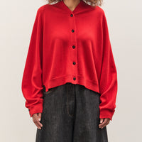 Person wearing a red cardigan over a black top on a plain background