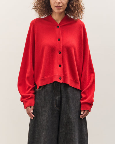 Person wearing a red cardigan over a black top on a plain background