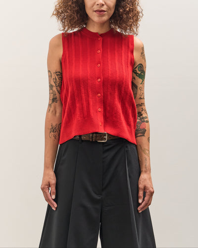 Person wearing a red sleeveless shirt and black pants on a plain background