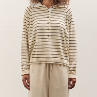 Woman wearing a striped shirt and beige pants against a plain background