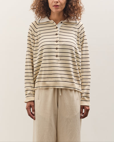 Woman wearing a striped shirt and beige pants against a plain background