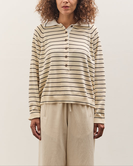Woman wearing a striped shirt and beige pants against a plain background