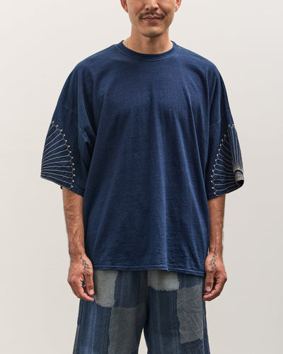 Man wearing a blue t-shirt with unique sleeve designs on a plain background