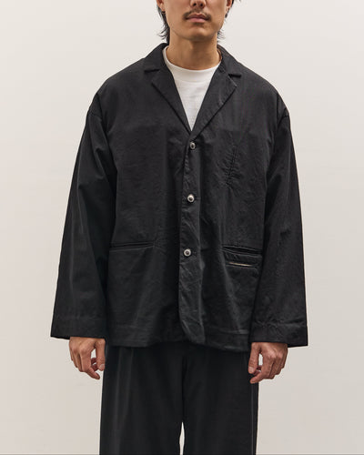 Man wearing a black jacket and glasses against a plain background