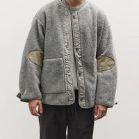 Man wearing a gray fleece jacket with patchwork design on a white background