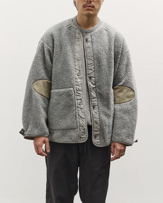 Man wearing a gray fleece jacket with patchwork design on a white background