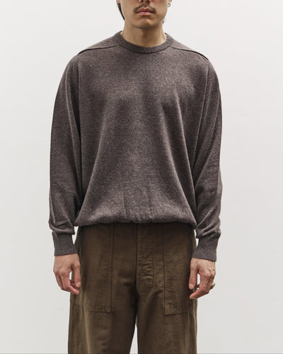 Man wearing a brown sweater and sunglasses against a plain background