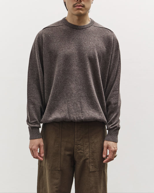 Man wearing a brown sweater and sunglasses against a plain background